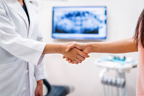 Doctor and patient doing handshake in clinic stock photo