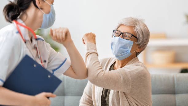 Doctor and senior woman wearing facemasks Doctor and senior woman wearing facemasks during coronavirus and flu outbreak. Virus protection. COVID-2019. Taking on masks. elbow stock pictures, royalty-free photos & images