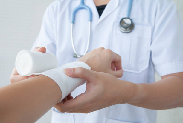 Doctor bandaging the wrist. Concept of first aids and treatment in wrist injuries. Closeup and selective focus on applying bandage onto patient's hand. burning stock pictures, royalty-free photos & images