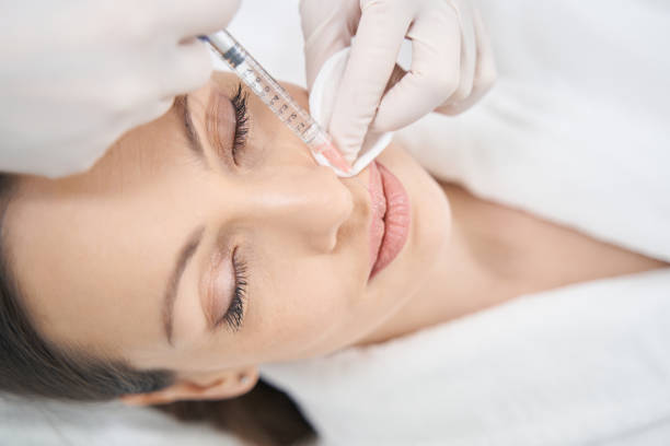 Doctor beautician doing beauty injection in woman lips stock photo