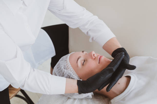 Doctor beautician makes a facial massage to a young woman. stock photo