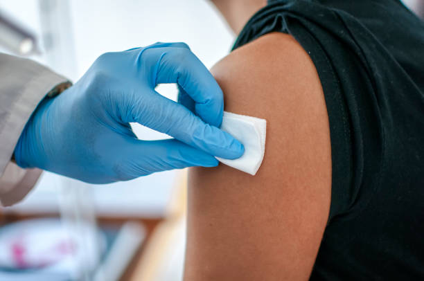 médico desinfecta la piel del paciente antes de la vacunación - vaccine mandate fotografías e imágenes de stock