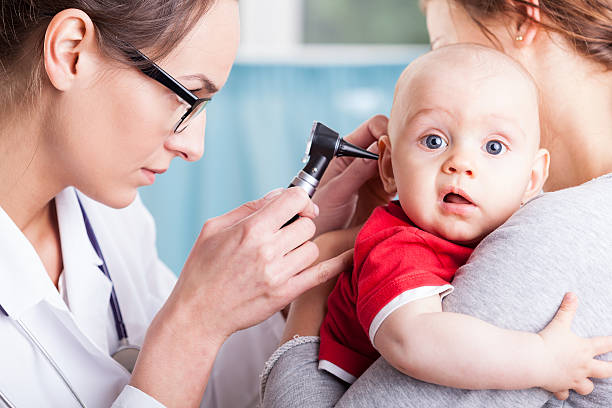 Doctor examining baby boy with otoscope Young doctor examining baby boy with otoscope human ear stock pictures, royalty-free photos & images