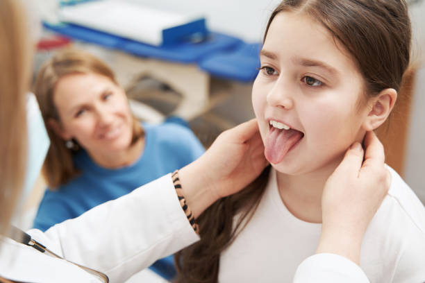 Doctor examining child lymph nodes and mouth in clinic stock photo