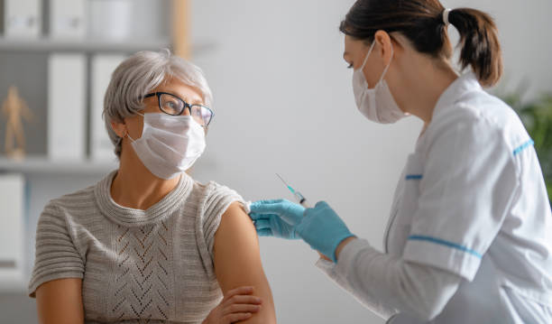 arts die een hogere vrouw een vaccinatie geeft - vaccinatie stockfoto's en -beelden