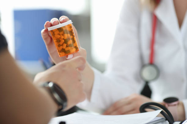 Doctor giving patient jar of medicine in clinic closeup stock photo