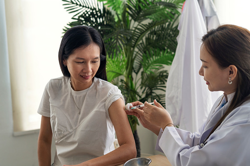 Asian female Patient Getting Vaccinated Injection During Doctor's Appointment In Hospital. Corona Virus Immunization