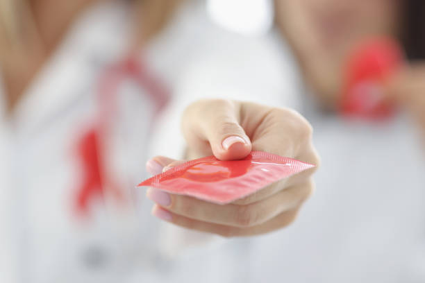 Doctor holding red condom in clinic closeup stock photo