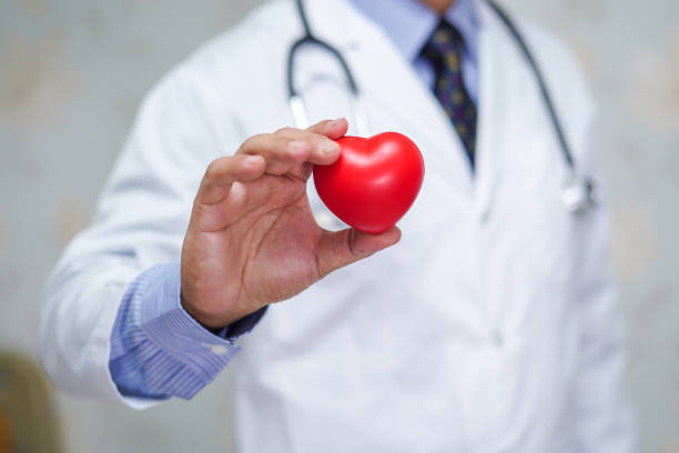 médico segurando coração vermelho na mão na enfermaria do hospital de enfermagem : conceito médico saudável e forte - cardiologista - fotografias e filmes do acervo