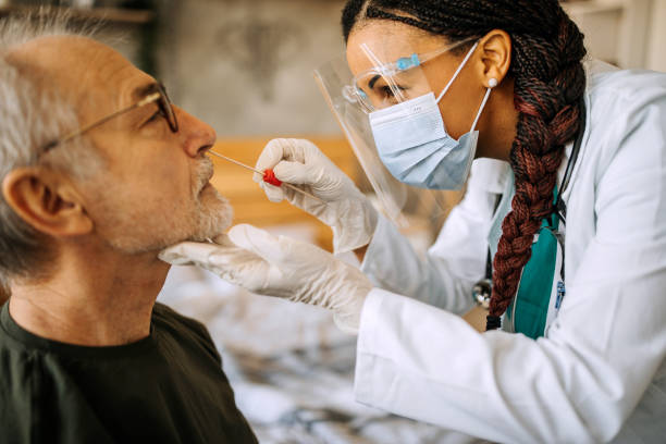 Doctor in a home visit to a senior man Doctor is in a home visit to a senior man and takes him sample for corona virus testing pandemic illness photos stock pictures, royalty-free photos & images