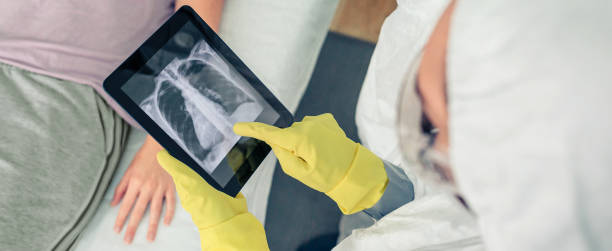 Doctor in protective suit examining x-ray of patient on tablet stock photo