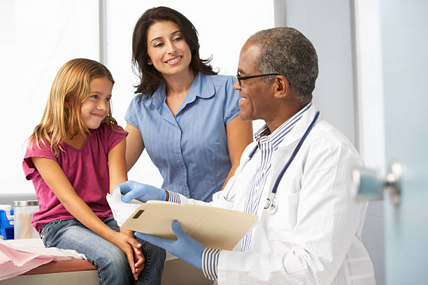 Doctor In Surgery Examining Young Girl Smiling Doctor In Surgery Examining Young Girl With Mother. general practitioner stock pictures, royalty-free photos & images