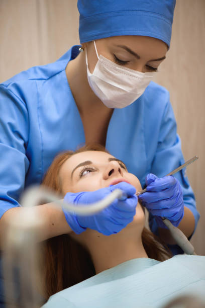 Doctor in uniform checking up female patient's teeth in dental clinic. stock photo