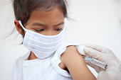 Doctor injecting vaccination on asian child girl arm. The child girl wearing protection mask for protect air smog pollution with PM 2.5 and Covid-19 virus. Healthy and medical concept.
