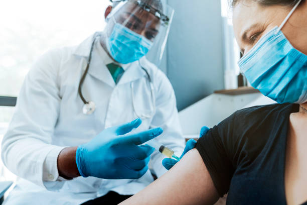 여성 환자의 팔에 백신을 주입하는 의사 - south africa covid 뉴스 사진 이미지