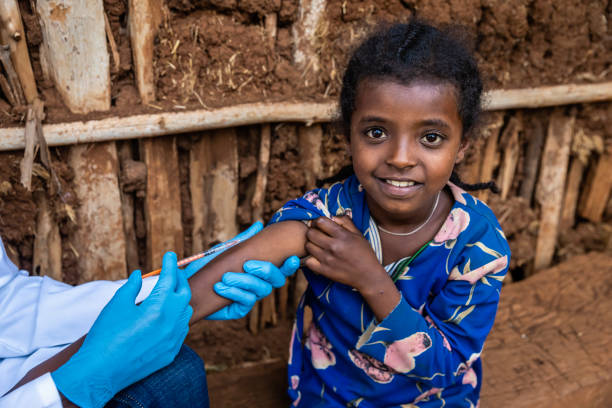 Doctor is doing an injection to young African girl in small village, East Africa stock photo