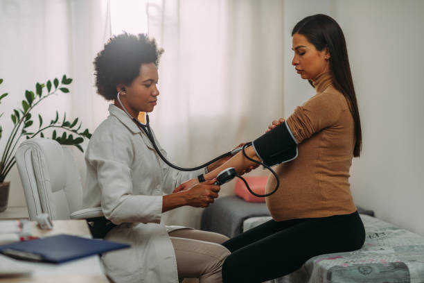 Doctor measuring blood pressure to pregnant woman African american doctor measuring blood pressure to pregnant woman. obstetrician photos stock pictures, royalty-free photos & images