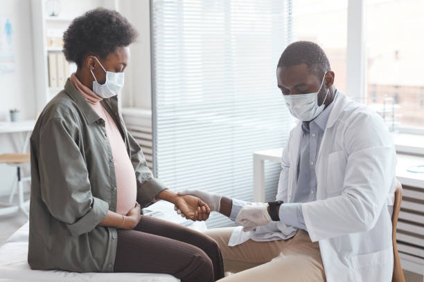 arts die de impuls van zwangere vrouw meet - arts vrouw mondkapje stockfoto's en -beelden