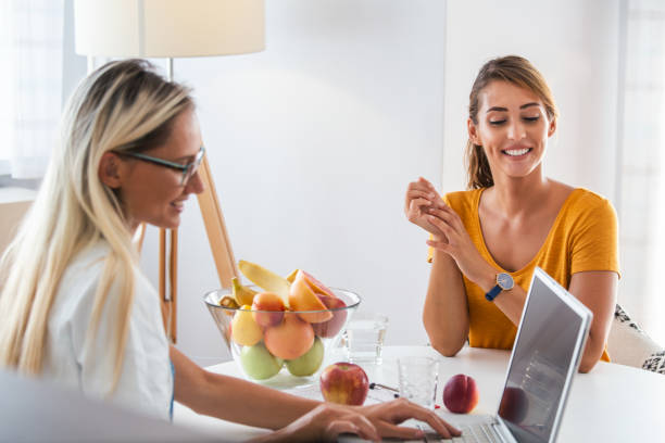 doctor nutritionist, dietician and female patient on consultation in the office. young smiling female nutritionist in the consultation room. nutritionist desk with healthy fruit and measuring tape. - natural food web imagens e fotografias de stock
