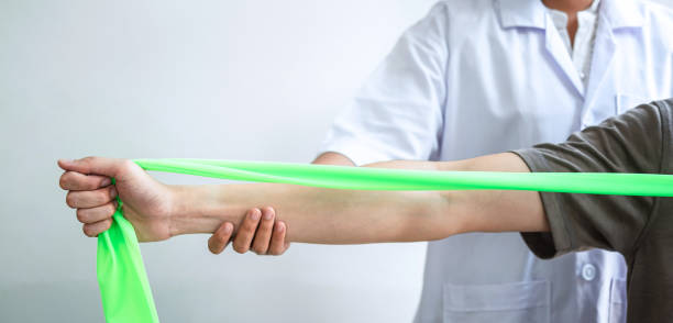 Doctor or Physiotherapist working examining treating injured arm of athlete male patient, stretching and exercise, Doing the Rehabilitation therapy pain in clinic stock photo