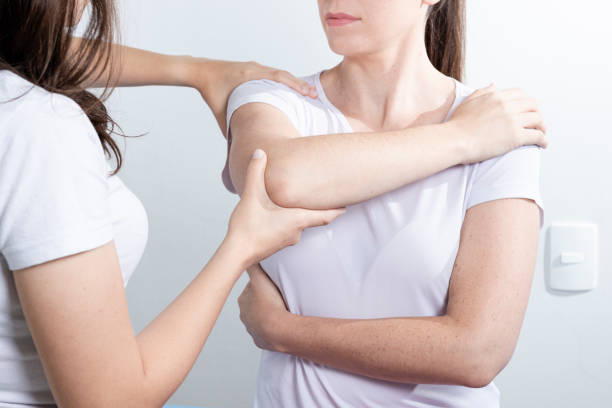 Doctor physiotherapist assisting a woman patient while giving exercising treatment massaging the arm of patient in a physio room. Rehabilitation physiotherapy concept"n stock photo