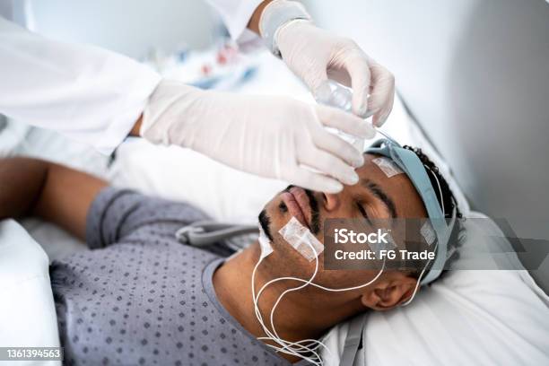 Doctor preparing patient in bed for polysomnography (sleep study)