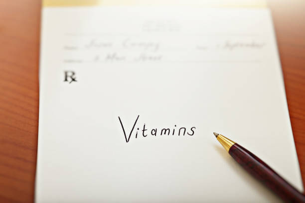 Doctor prescribes vitamins on a prescription pad, with pen stock photo