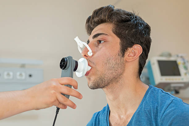 doctor reviews patient's lung capacity with a peak flow meter - longfunctie stockfoto's en -beelden