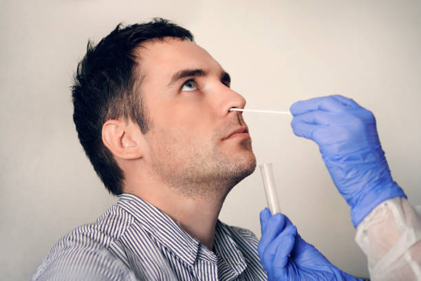 arzt, der nasenschleimprobe aus der männlichen nase durchführung atemvirus-testverfahren. überprüfung der nasenhöhle bei hno. - corona test stock-fotos und bilder
