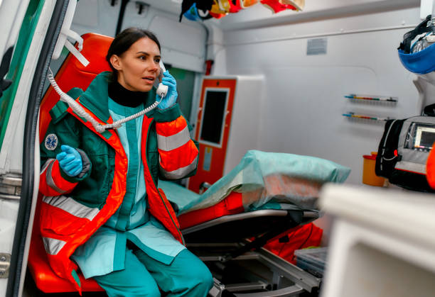 Doctor team. Medicine. Beautiful woman paramedic in uniform answers the phone call while sitting in a modern ambulance car. emergency response stock pictures, royalty-free photos & images