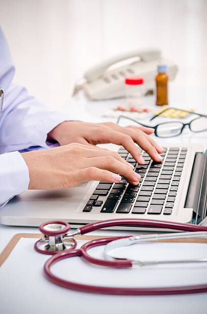doctor typing on computer stock photo