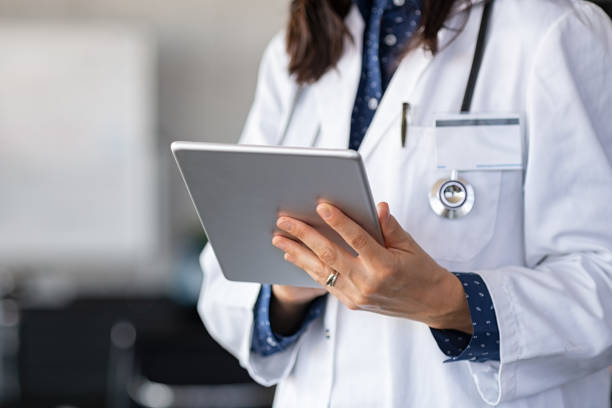 Doctor using digital tablet Close up of woman doctor hands using digital tablet at clinic. Closeup of female doctor in labcoat and stethoscope holding digital tablet, reading patient report. Hands holding medical report, copy space. physician stock pictures, royalty-free photos & images