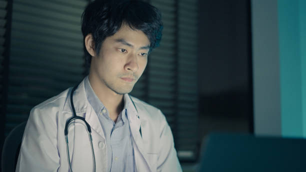 Doctor using laptop late at night in clinic stock photo