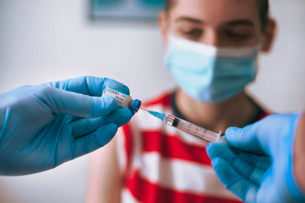 Doctor vaccinating a teenage boy stock photo