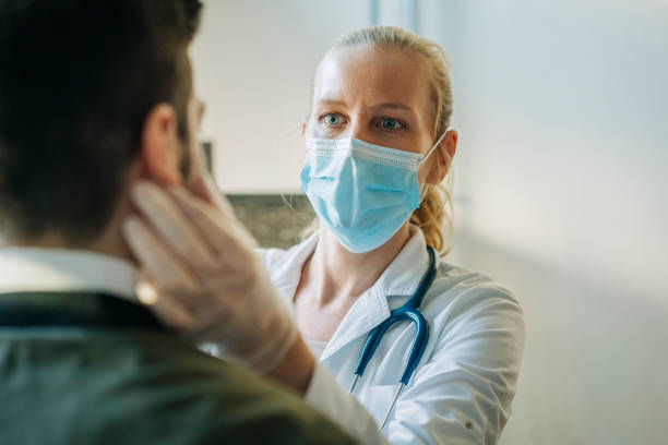 Doctor wearing surgical mask examining man Female doctor wearing surgical mask examining infected patient. Mature healthcare worker checking mid adult man. They are at pharmacy. patient stock pictures, royalty-free photos & images