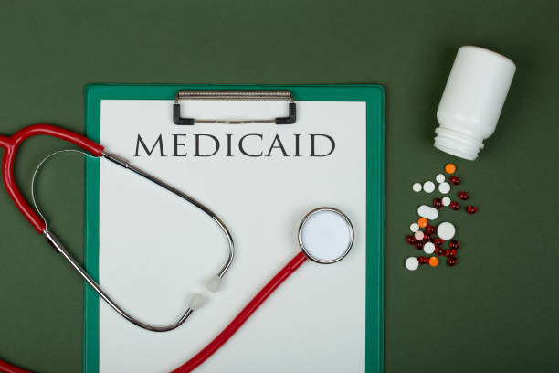 Doctor workplace - red stethoscope, pills, medical bottle and clipboard with text "medicaid" stock photo