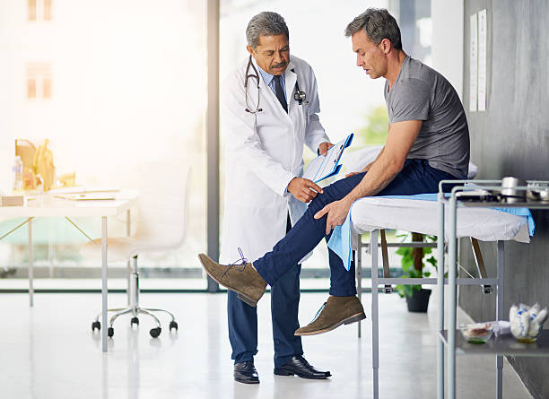 Doctor’s do it for the health of it Shot of a mature doctor examining his patient who is concerned about his knee joint pain stock pictures, royalty-free photos & images