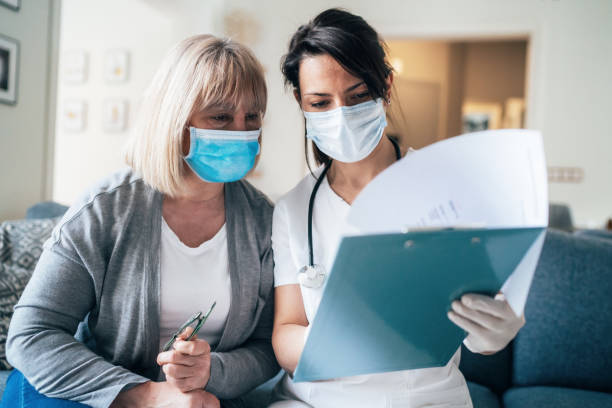 Doctor's home visiting during the quarantine Female doctor consults mature patient during the quarantine for coronavirus visit stock pictures, royalty-free photos & images