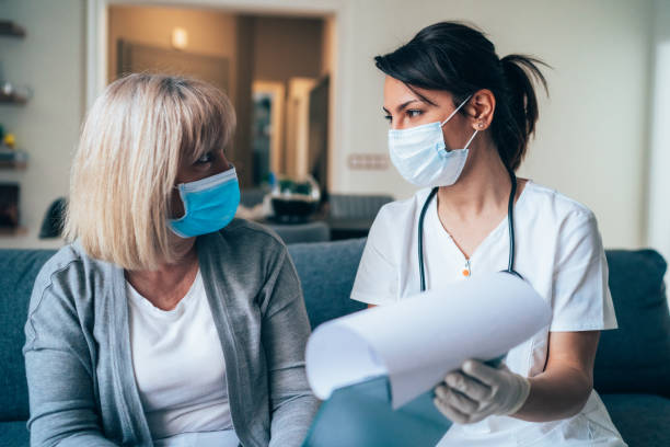 Doctor's home visiting during the quarantine Female doctor consults mature patient during the quarantine for coronavirus woman talking to doctor stock pictures, royalty-free photos & images