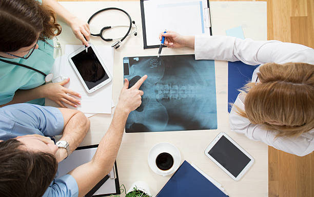 Doctors interpreting x-ray image Doctors sitting around the table and interpreting x-ray image bone fracture stock pictures, royalty-free photos & images