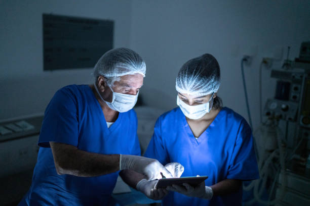 Doctors using digital tablet at surgery on hospital Doctor doing eye surgery of patient in hospital medical scrubs photos stock pictures, royalty-free photos & images