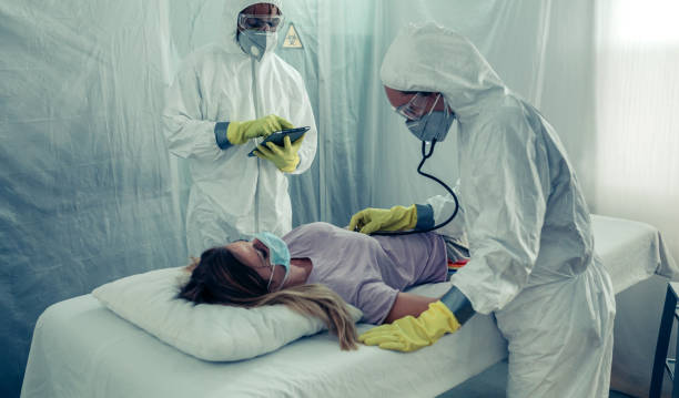 Doctors with bacteriological protection suits attending a patient Doctors with bacteriological protection suits attending a patient infected with a virus pandemic illness stock pictures, royalty-free photos & images
