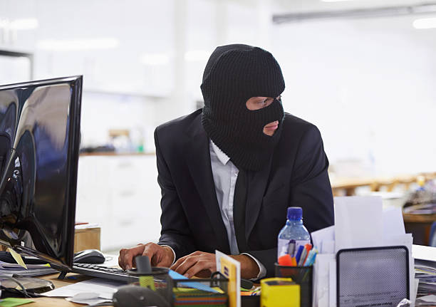 Doing some illegal activities... Shot of a hacker dressed in a black mask hacking a computerhttp://195.154.178.81/DATA/i_collage/pi/shoots/783303.jpg ski mask criminal stock pictures, royalty-free photos & images