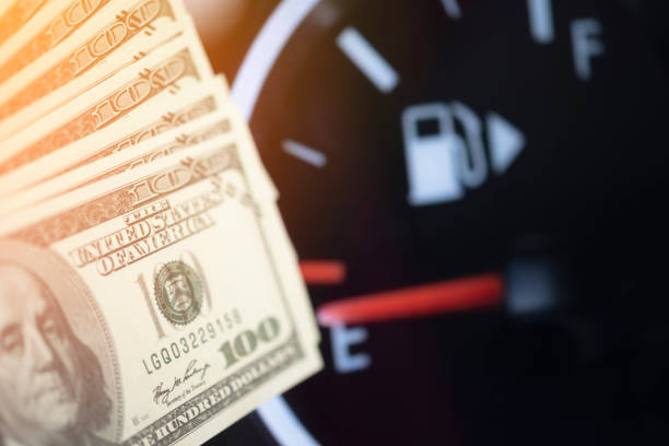 Dollar bills against oil mileage dashboard background stock photo
