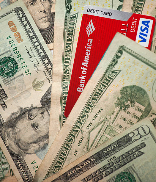 Dollar bills and Debit card Los Angeles, California, USA- April 17, 2014: A pile US Dollars and a Bank of America Visa debit card. bank of america stock pictures, royalty-free photos & images