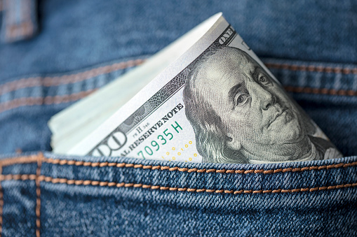 Close-up of US $100 dollar bills in jeans pocket.