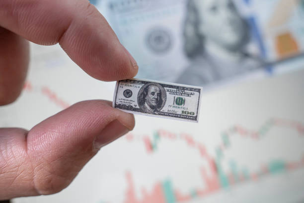 dollar inflation. man holds a small bill of one hundred dollars against the background of a falling chart on the stock exchange. Low income from trading on the stock exchange. Bankruptcy stock photo
