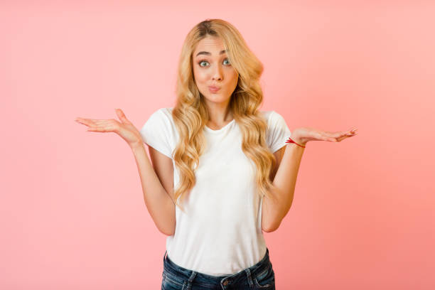 I don't know. Unsure woman shrugging shoulders I don't know. Unsure woman shrugging shoulders over pink studio background ignorance stock pictures, royalty-free photos & images