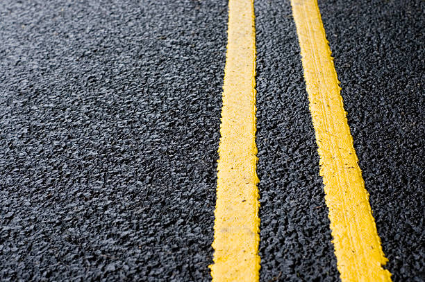 Double Yellow Line Close-up on yellow lines painted on fresh black tarmac. dividing line road marking stock pictures, royalty-free photos & images