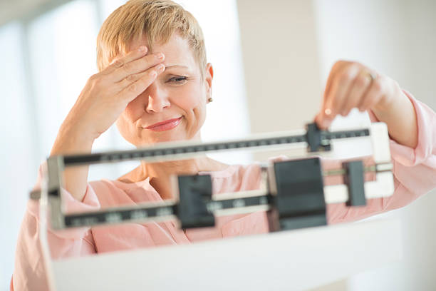 Doubtful Woman Adjusting Weight Scale stock photo